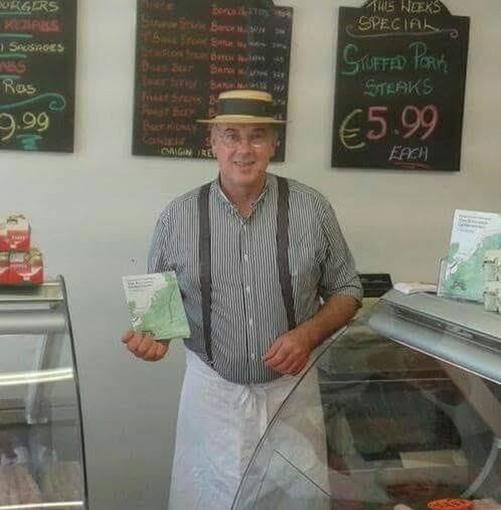 Gerry behind the glass counter in the Kilcoole shop, with chalkboards for burgers, kebabs, sausages and Irish beef